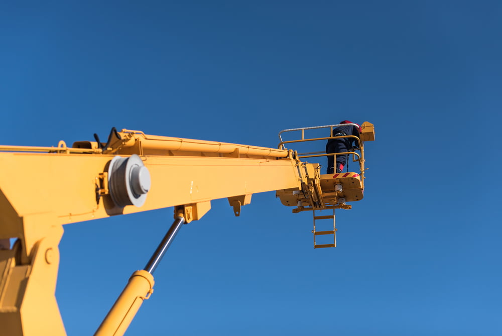 A worker is standing on the platform of a boom lift