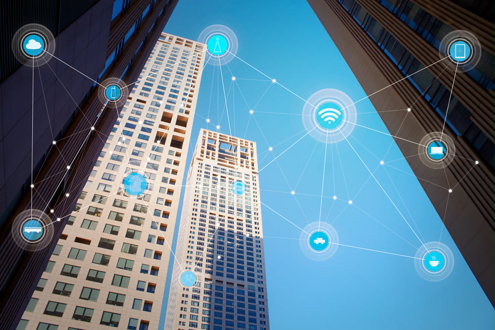 Looking to the sky, highrise buildings feature with graphics of smart connected devices overlaid