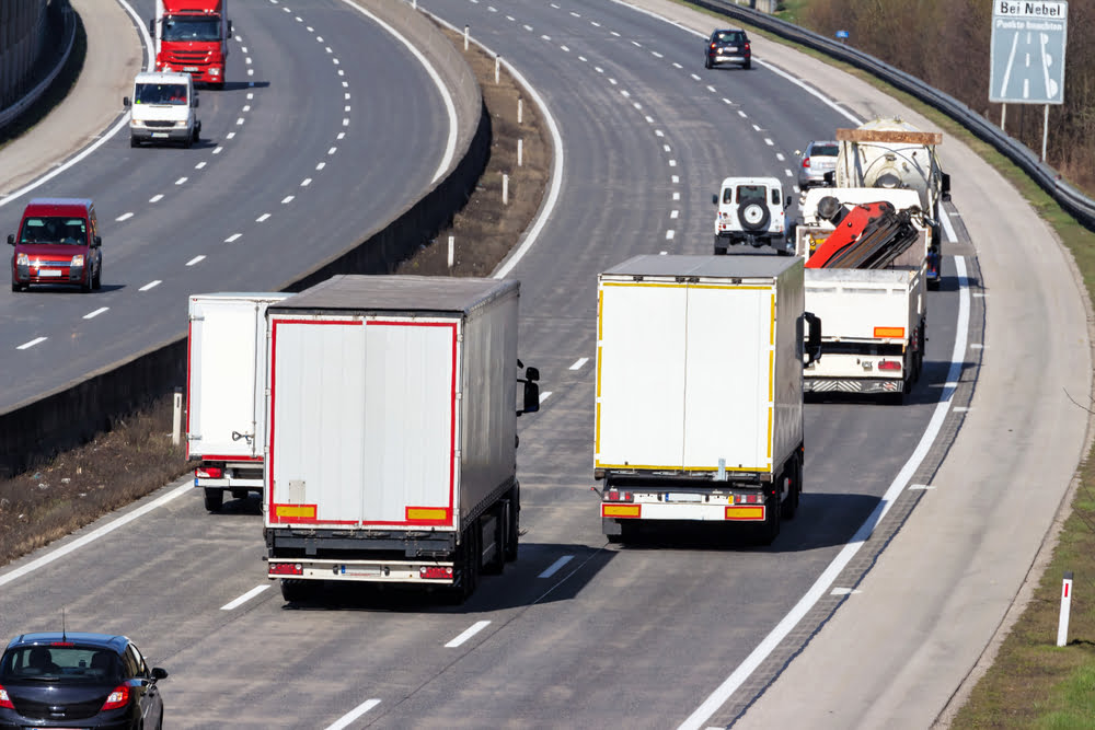 Trucks and cars on driving on a three lane highway.