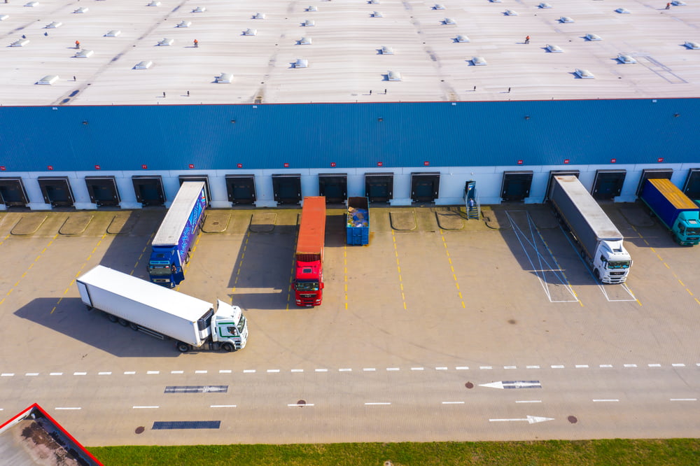 An aerial view of a warehouse showing a number of trucks being loaded with goods.