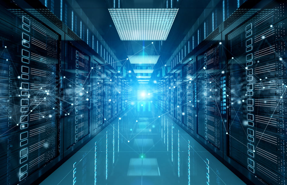 A view down the walkway of a large, secure server room with blue light in the distance