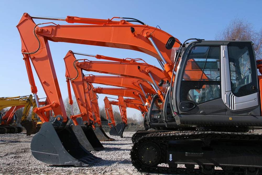 A fleet of diggers and construction equipment parked outside