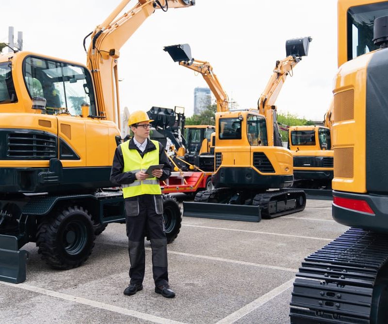 A field technician inspects construction equipment, leveraging integrated telematics to monitor performance and streamline maintenance