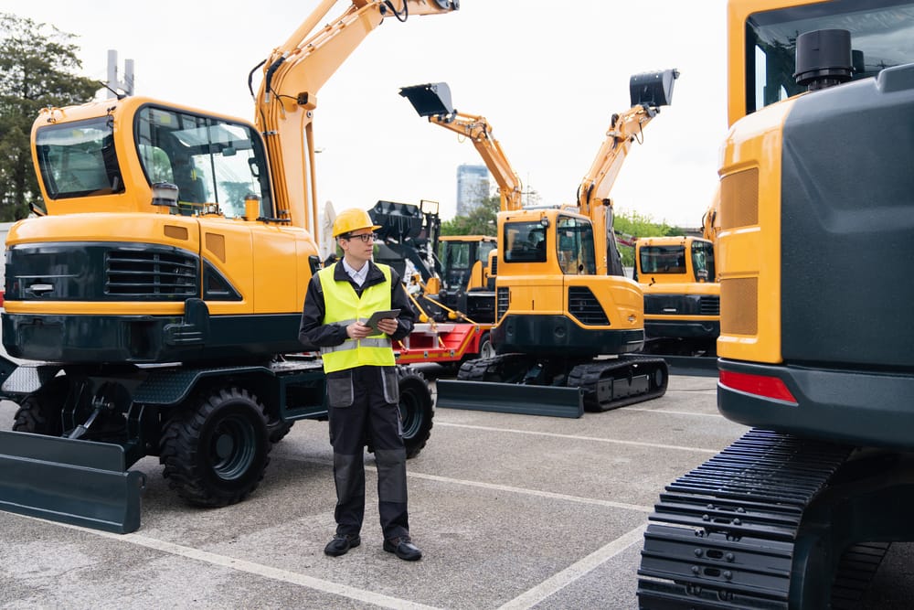 A field technician inspects construction equipment, leveraging integrated telematics to monitor performance and streamline maintenance