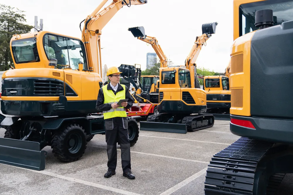 A field technician inspects construction equipment, leveraging integrated telematics to monitor performance and streamline maintenance
