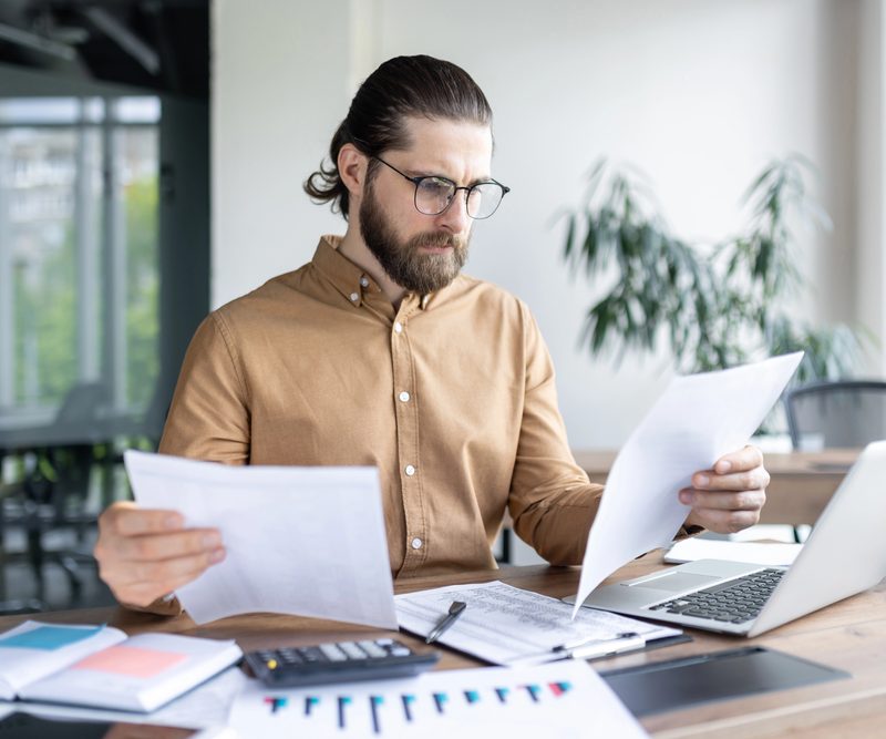 A fleet manager in an office looks over paperwork and manual checklists