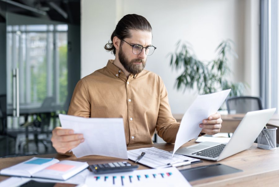 A fleet manager in an office looks over paperwork and manual checklists