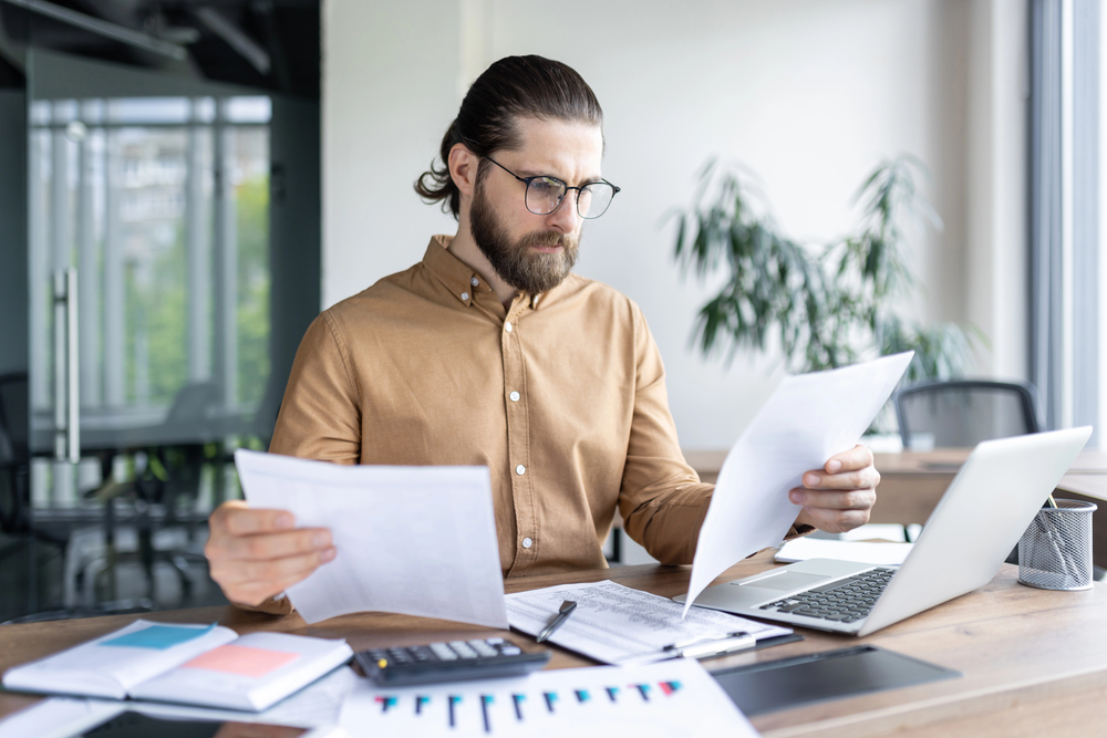 A fleet manager in an office looks over paperwork and manual checklists
