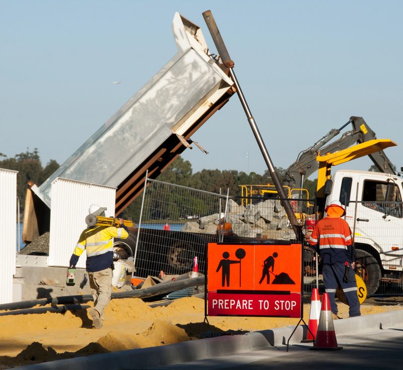 Worker using a mobile device at a construction site, supported by real-time alerts and insights from construction site safety software.
