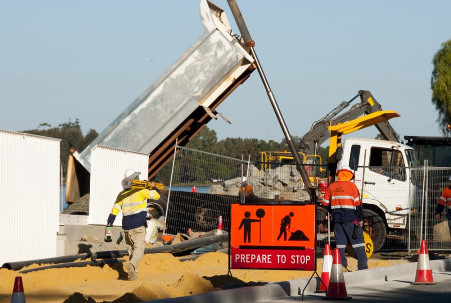 Worker using a mobile device at a construction site, supported by real-time alerts and insights from construction site safety software.