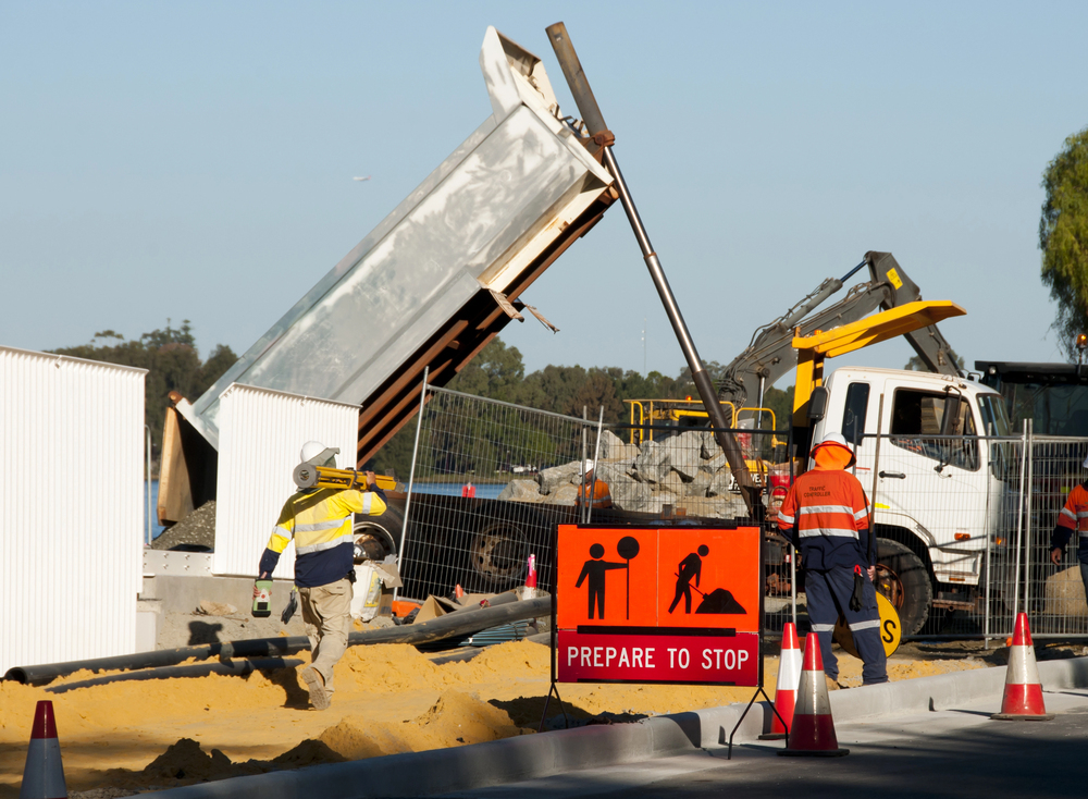Worker using a mobile device at a construction site, supported by real-time alerts and insights from construction site safety software.