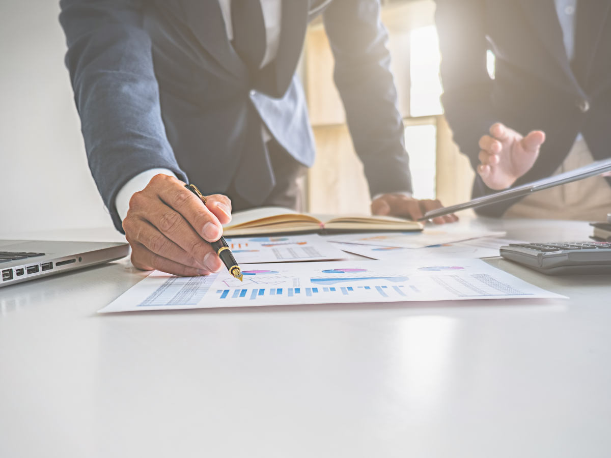 Two professionals reviewing charts and data reports at a desk, illustrating how asset management compliance software​ supports audit accuracy and operational efficiency