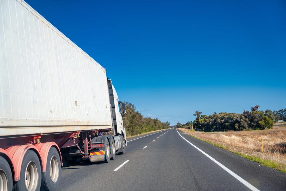 Heavy vehicle driving on an open highway, representing long-haul transport operations enhanced by auto telematics for location tracking and performance monitoring.