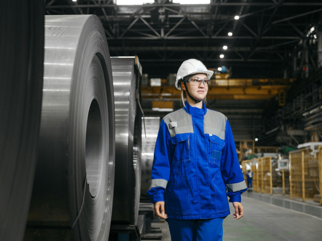 A factory manager in protective clothing walks through an industrial facility, considering IoT platform options for improving automation and operational efficiency