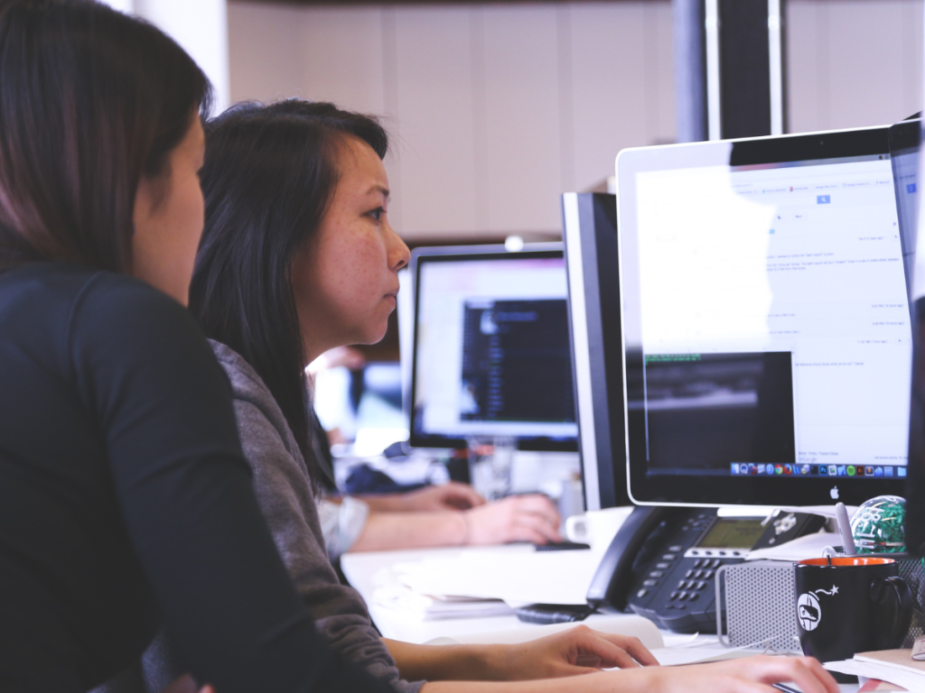 Two operations professionals at a computer trying to answer the question, how does Inauro’s Perspio compare to Rayven’s data platform?