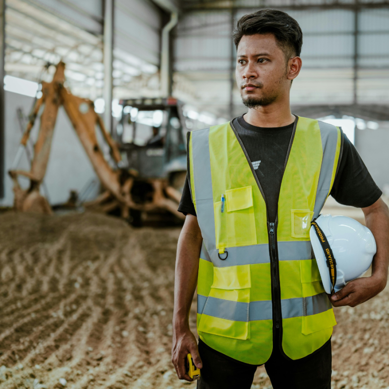 A construction stands in front of construction equipment in a large construction site