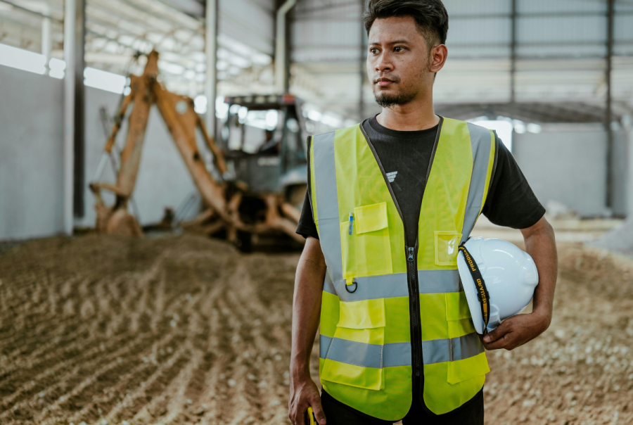 A construction stands in front of construction equipment in a large construction site