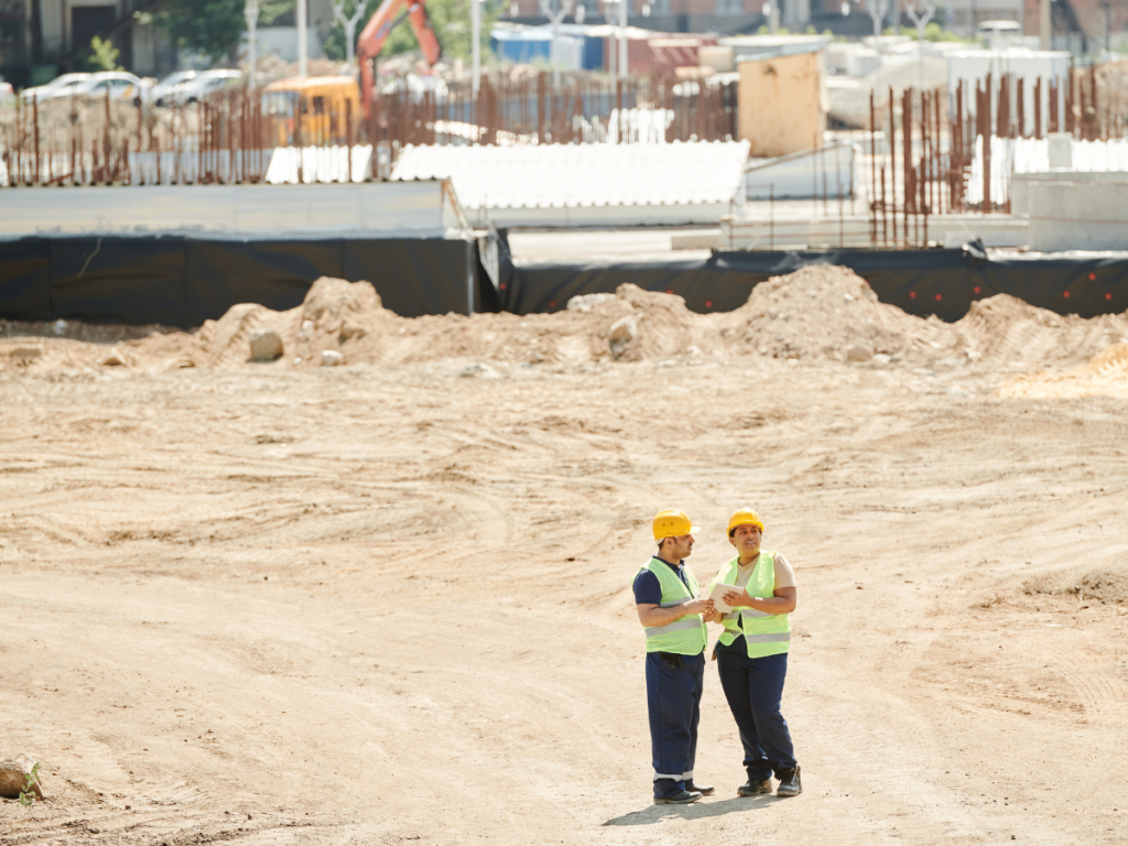 Two workers standing on a construction site reviewing plans, illustrating how IoT platforms like Inauro connect diverse data systems for real-time operational visibility
