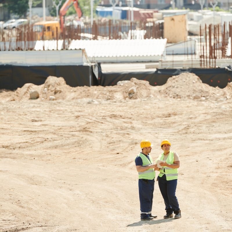 Two workers standing on a construction site reviewing plans, illustrating how IoT platforms like Inauro connect diverse data systems for real-time operational visibility