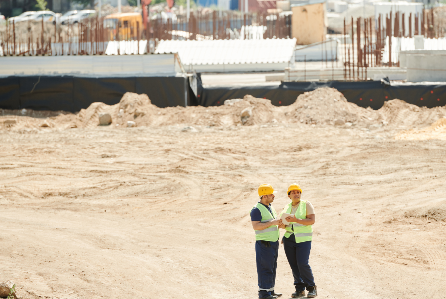 Two workers standing on a construction site reviewing plans, illustrating how IoT platforms like Inauro connect diverse data systems for real-time operational visibility